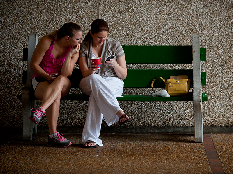 Two people on a bench looking at a smart phone Two people on a bench looking at a smart phone