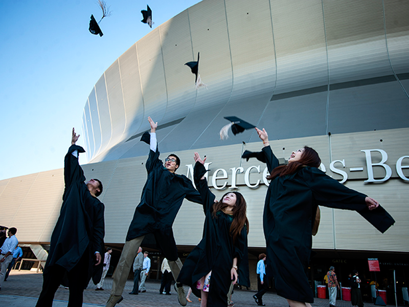 Graduates throw their caps in the air outside the Mercedes-Benz Superdome Graduates throw their caps in the air outside the Mercedes-Benz Superdome