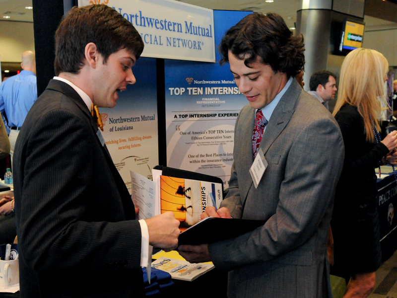 A recruiter and student look over information packet at job fair A recruiter and student look over information packet at job fair