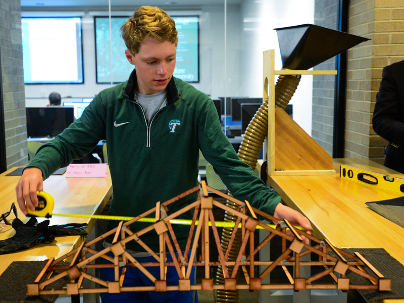 engineering Student uses measuring tape while participating in truss building